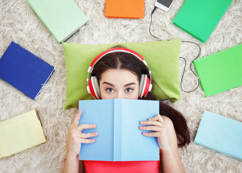 a woman lying on the floor with headphones over her face and a book