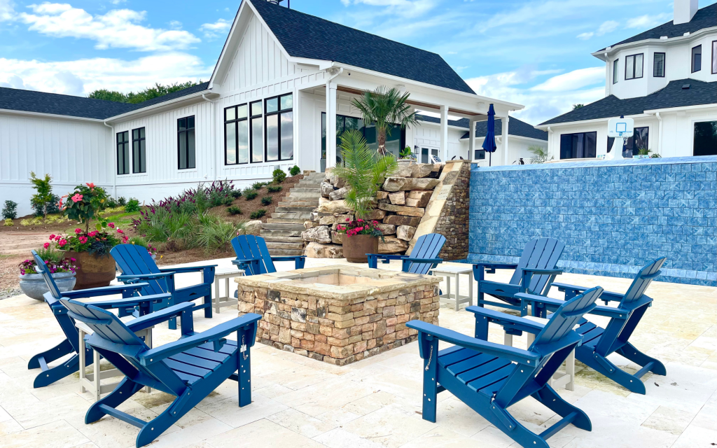 a white house with blue chairs and a fire pit