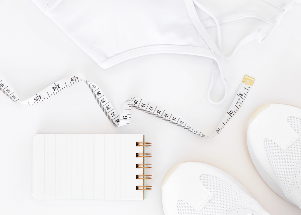 a white tape measure and a notebook with a garment and sneakers