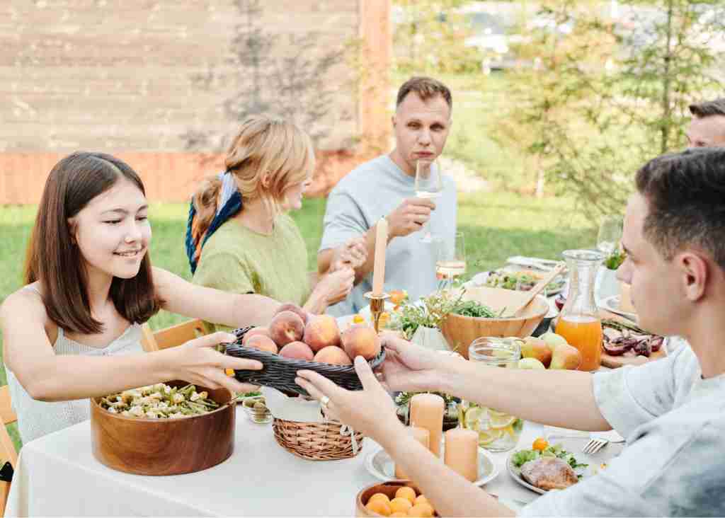 Plan time with family outdoors and eat a meal a group of people at a table with food and drinks