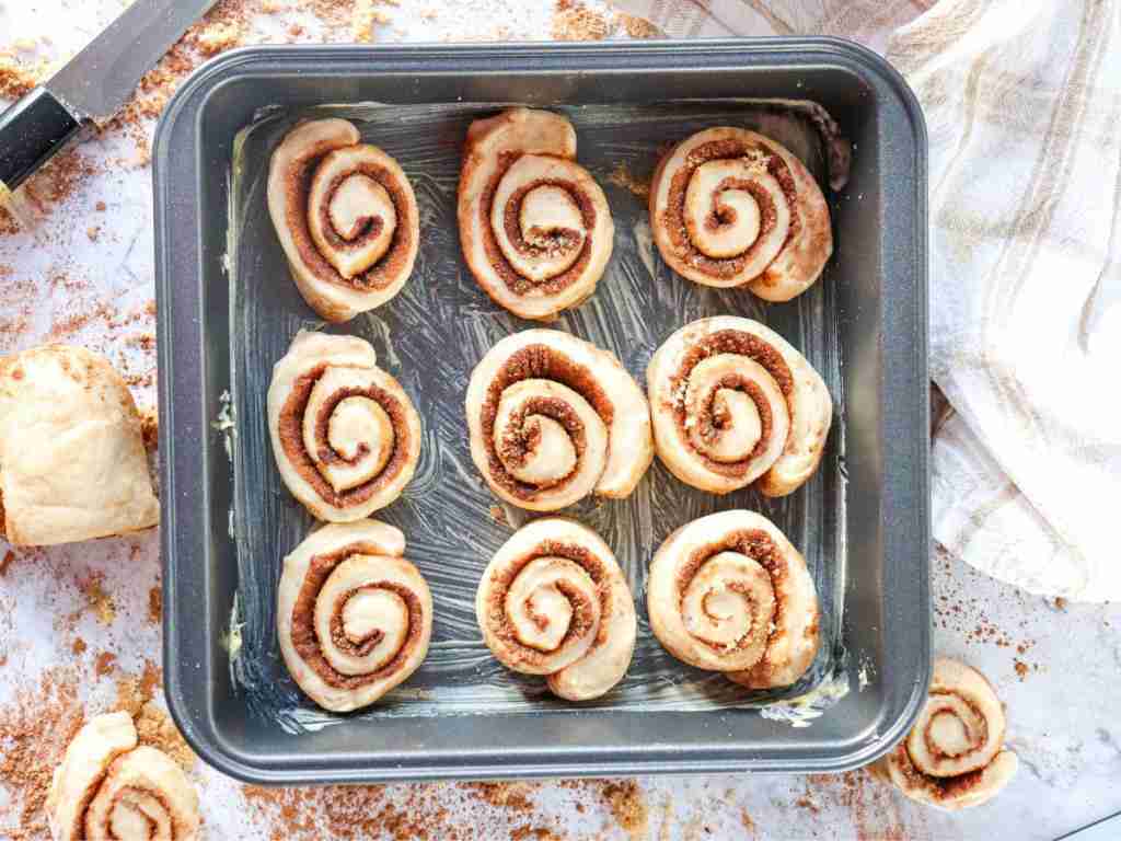 greased baking dish a tray of cinnamon rolls