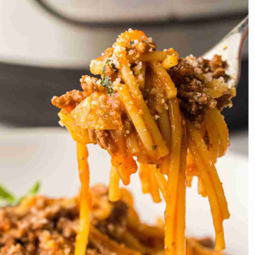 a fork holding spaghetti with meat and sauce