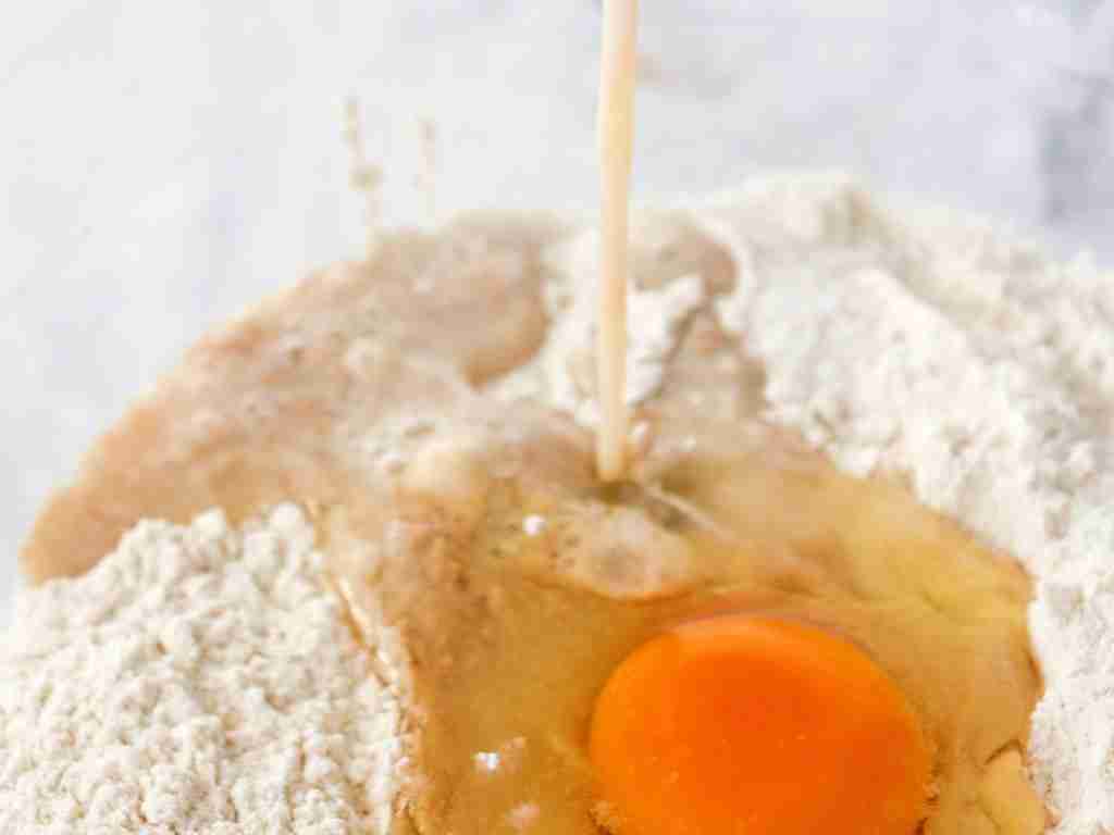 cinnamon rolls a egg being poured into a bowl of flour