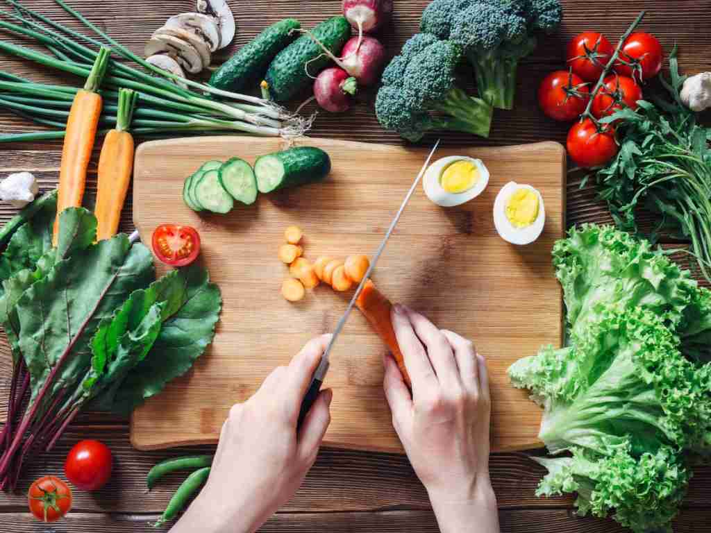 woman cutting up vegetables a person cutting vegetables on a cutting board