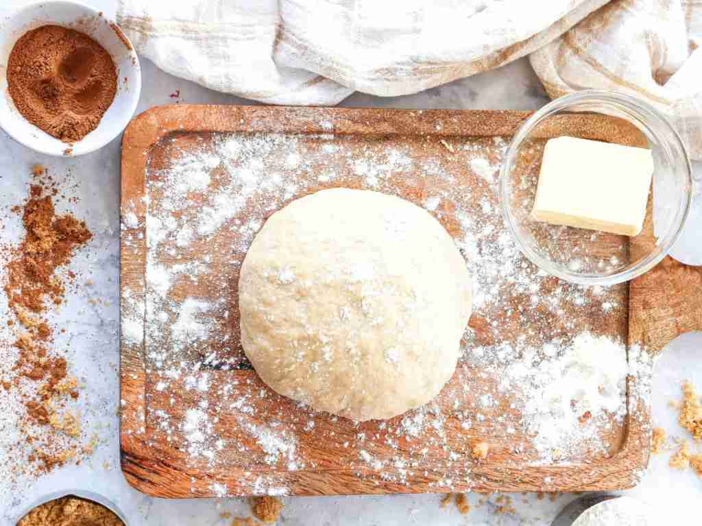 cinnamon roll recipe a dough on a cutting board with a butter and flour