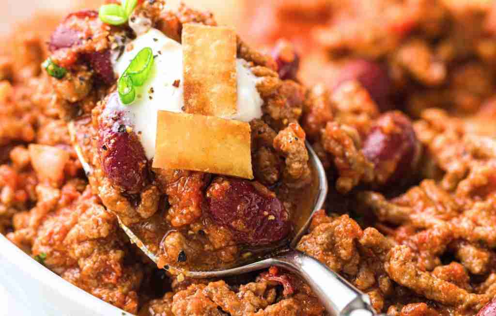 Spoon full of chili Hearty chili with toppings and garnish