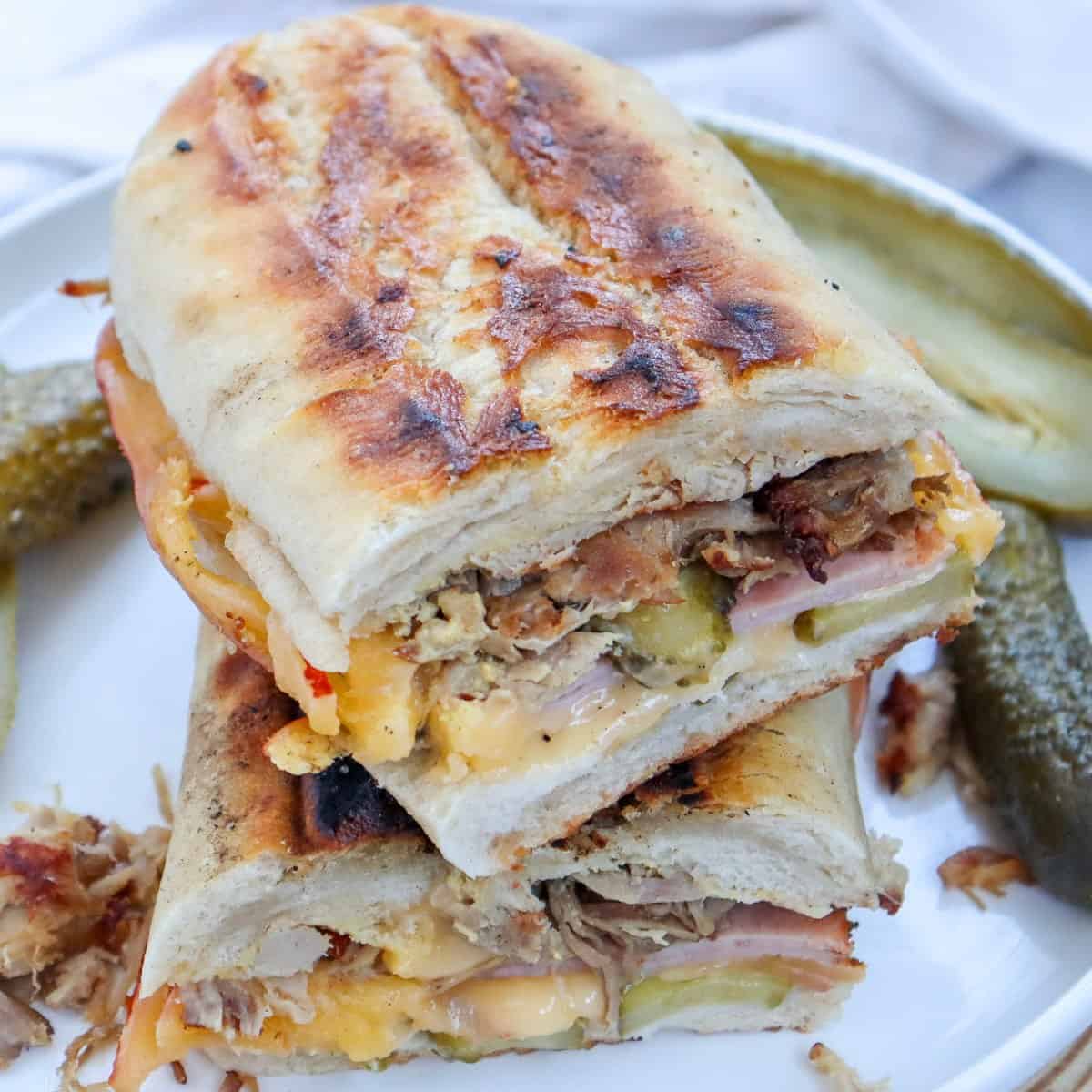 Cuban Sandwich on a white plate with pickles