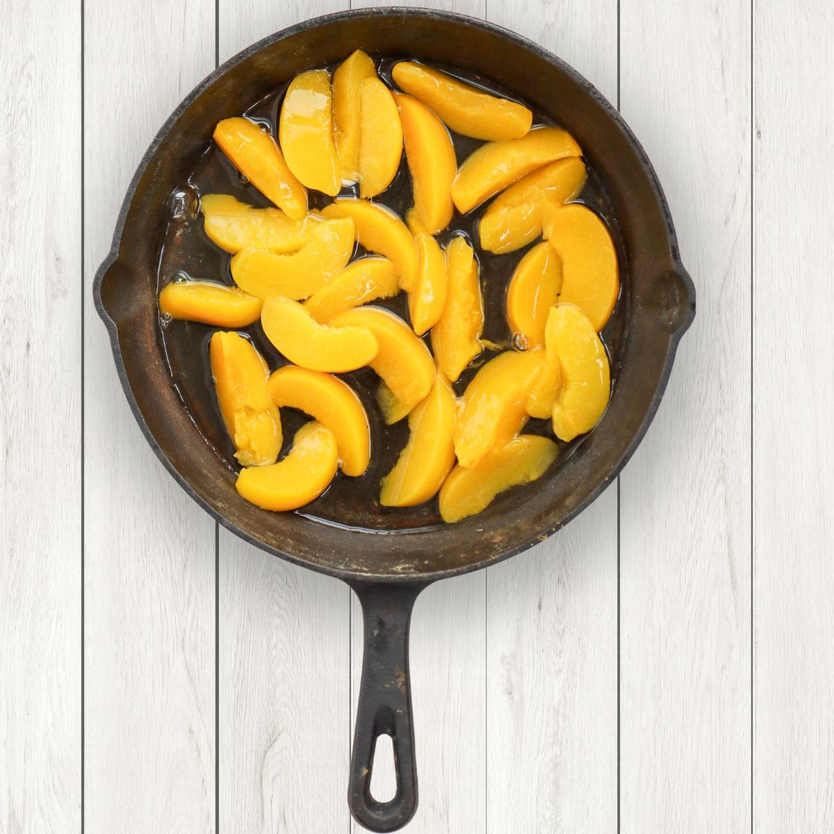 Sliced peaches in a black skillet on a table