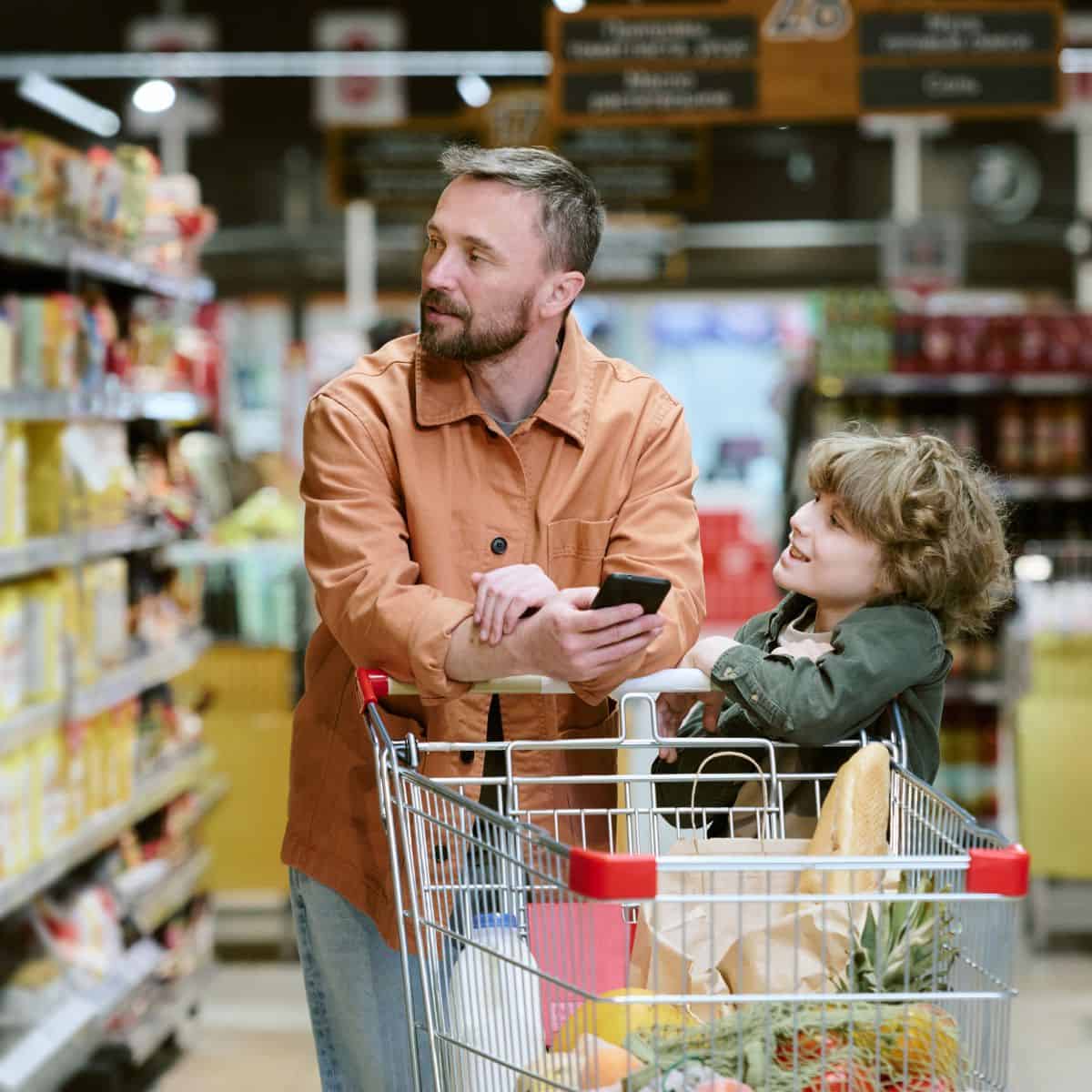 Use a weekly meal planning template for the grocery store A man and his child pushing a grocery cart in a grocery store aisle