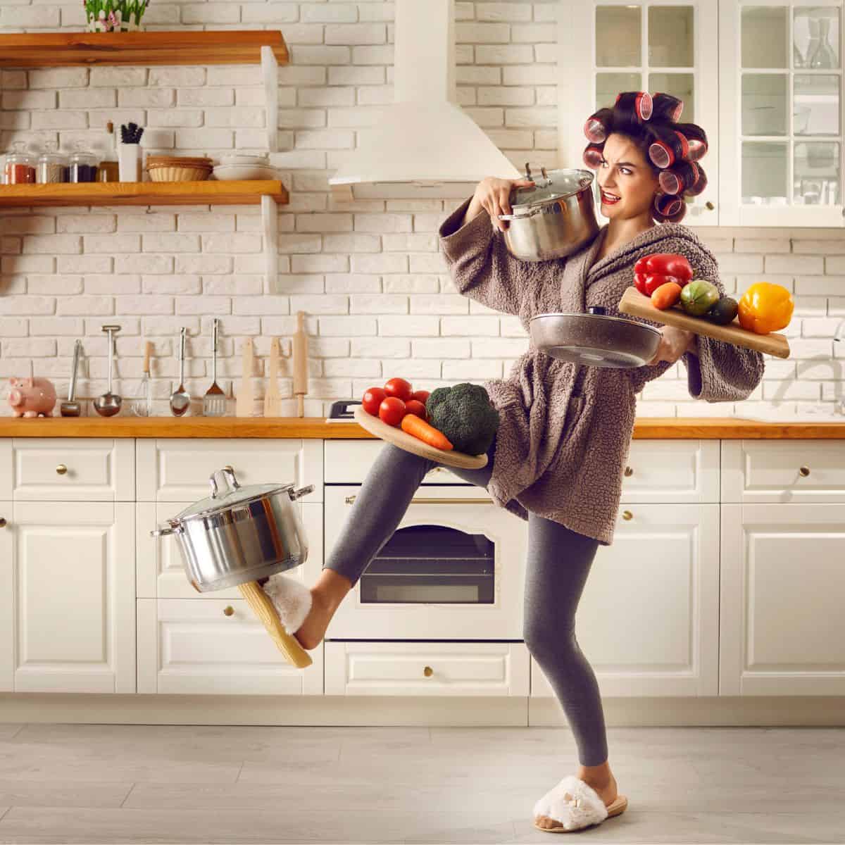 A busy Mom's weekly dinner plan A woman in her kitchen balancing pots, pans, and vegetables on her body.
